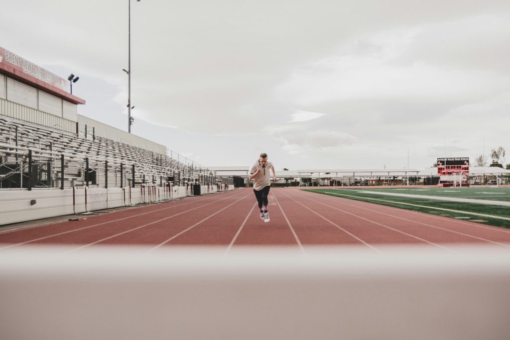 woman in black long sleeve shirt and black pants running on track field during daytime